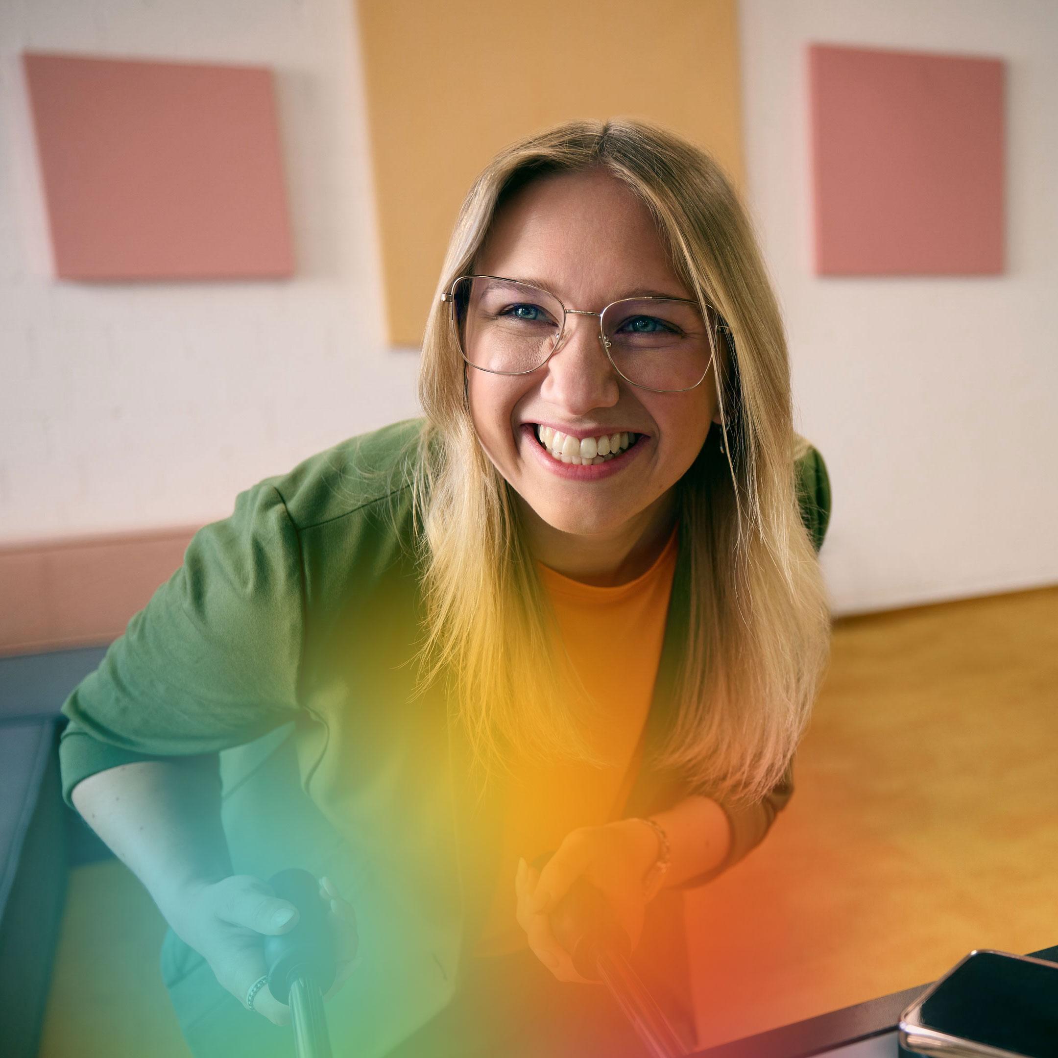 : A person leaning forward and holding the handle of a football table in a brightly colored room.